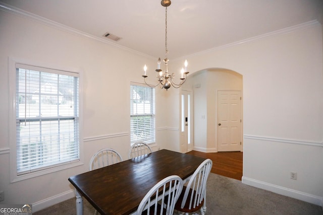 dining area with an inviting chandelier, a wealth of natural light, and ornamental molding