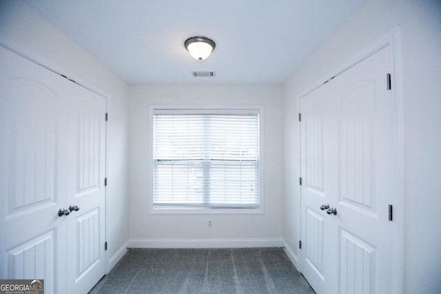 interior space with plenty of natural light and dark colored carpet