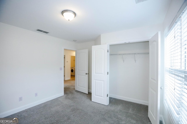 unfurnished bedroom with carpet, washer / dryer, and a closet