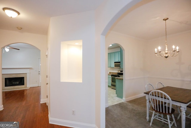 dining space with dark hardwood / wood-style floors, ceiling fan with notable chandelier, and ornamental molding