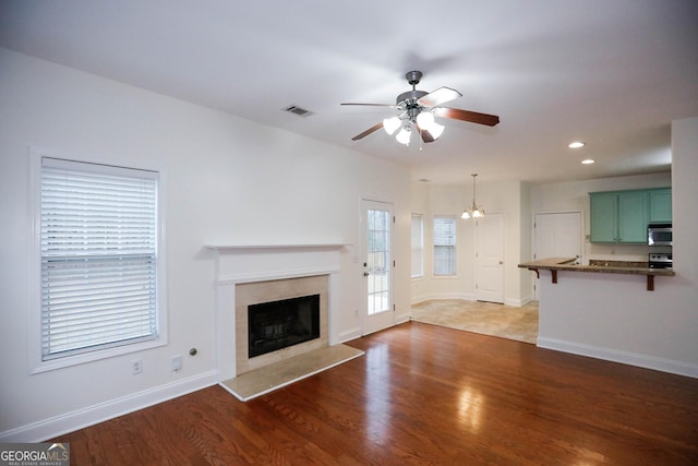 unfurnished living room featuring hardwood / wood-style flooring, ceiling fan, and a high end fireplace