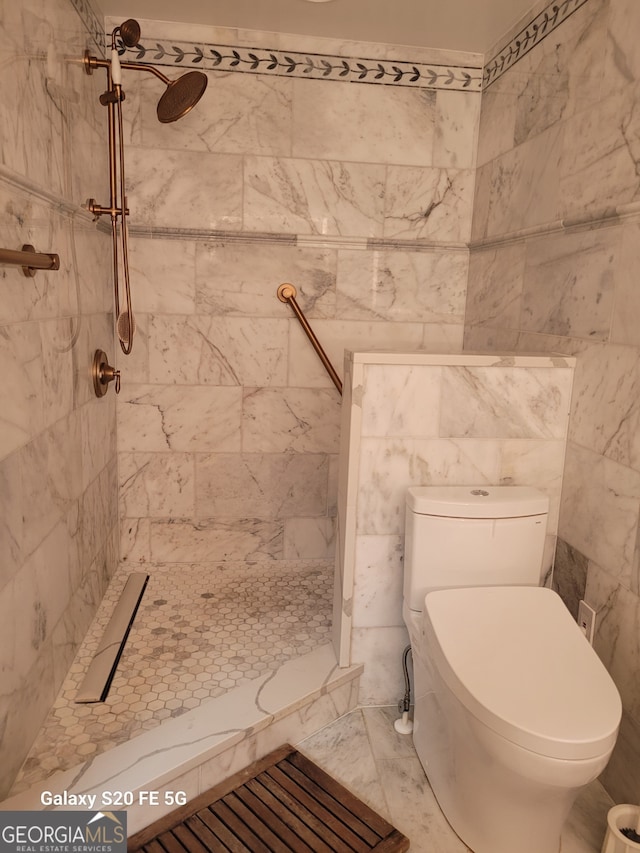 bathroom with a tile shower and toilet