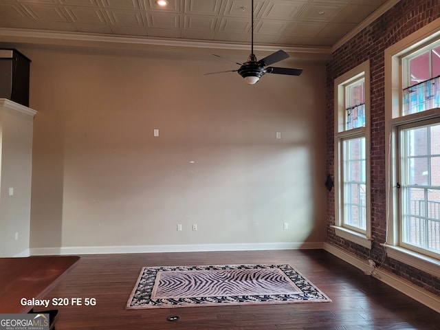 unfurnished room featuring ceiling fan, dark hardwood / wood-style flooring, and brick wall