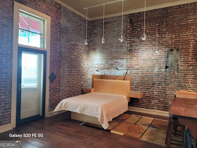 bedroom with crown molding, dark wood-type flooring, and brick wall