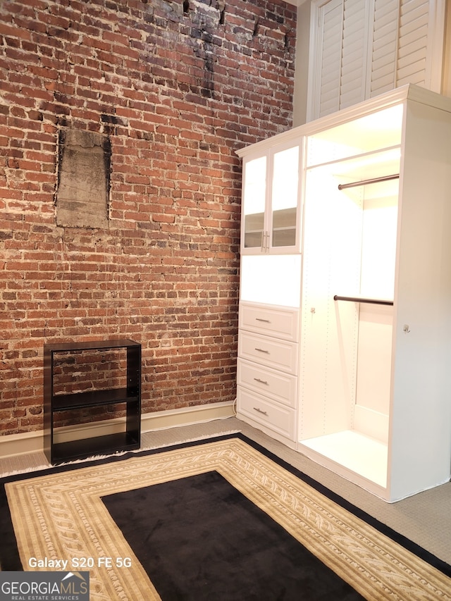 unfurnished living room featuring brick wall