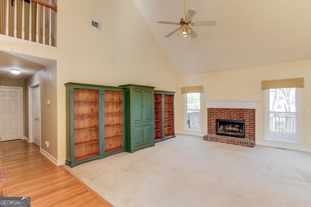 living room with a fireplace, high vaulted ceiling, ceiling fan, and a healthy amount of sunlight