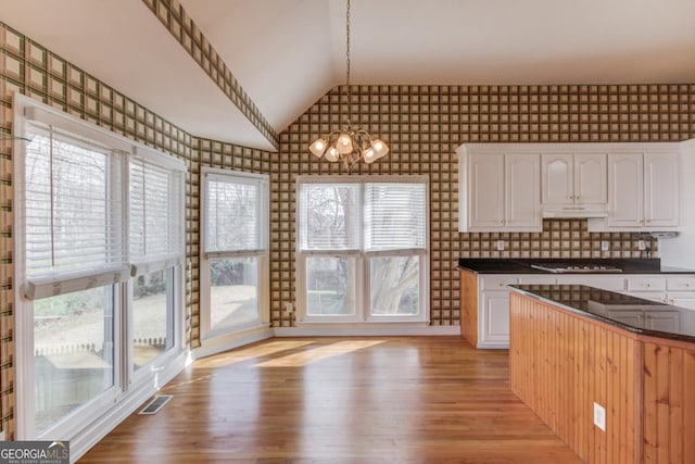 kitchen with backsplash, decorative light fixtures, white cabinetry, and gas stovetop