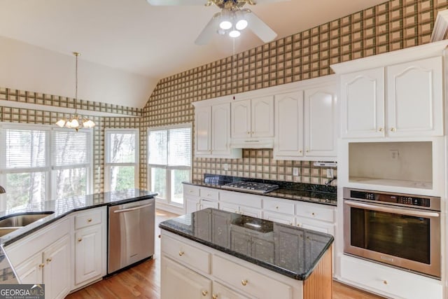 kitchen with stainless steel appliances, sink, decorative light fixtures, a center island, and white cabinetry