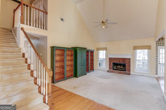 unfurnished living room with a fireplace, hardwood / wood-style flooring, high vaulted ceiling, and ceiling fan