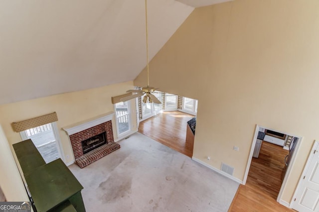 living room with ceiling fan, a fireplace, light hardwood / wood-style floors, and lofted ceiling