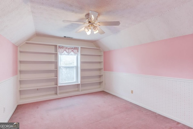 bonus room with a textured ceiling, built in features, ceiling fan, and lofted ceiling