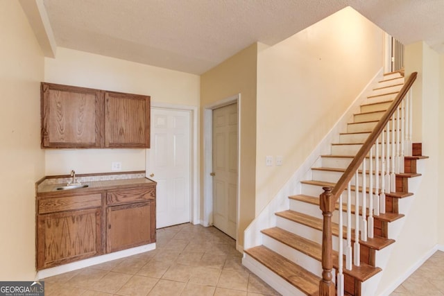 kitchen featuring light tile patterned flooring, a textured ceiling, and sink