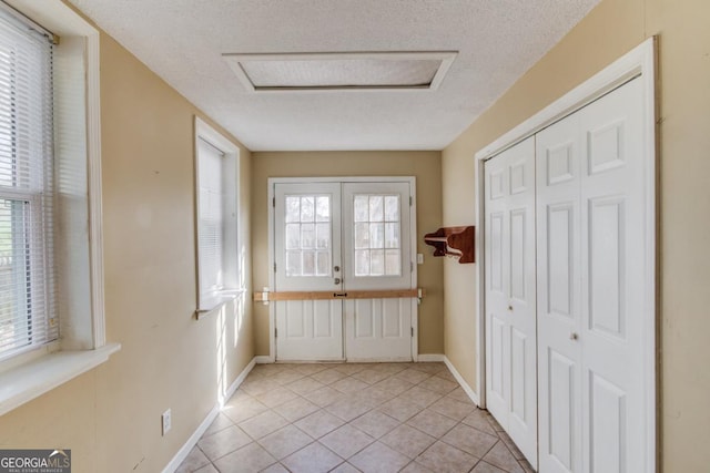 entryway featuring light tile patterned floors and a textured ceiling