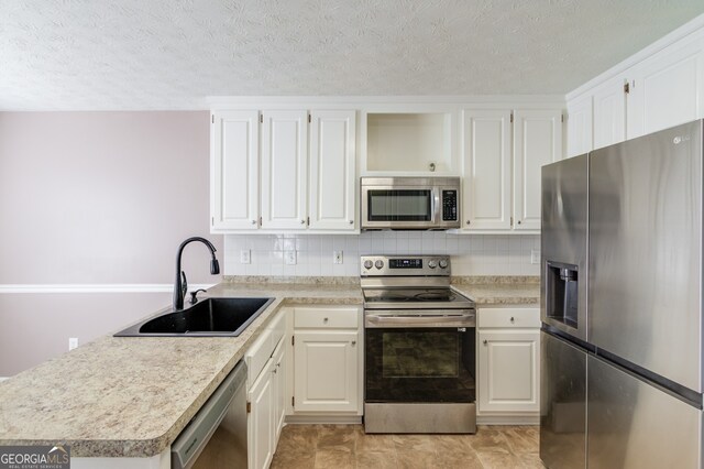 kitchen with appliances with stainless steel finishes, tasteful backsplash, a textured ceiling, sink, and white cabinets