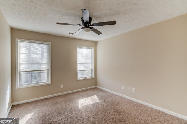 spare room featuring ceiling fan, carpet floors, and a textured ceiling