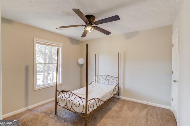 bedroom with a textured ceiling, carpet floors, and ceiling fan