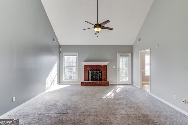 unfurnished living room featuring plenty of natural light, light colored carpet, high vaulted ceiling, and a brick fireplace