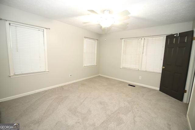 interior space featuring ceiling fan, light colored carpet, and a textured ceiling