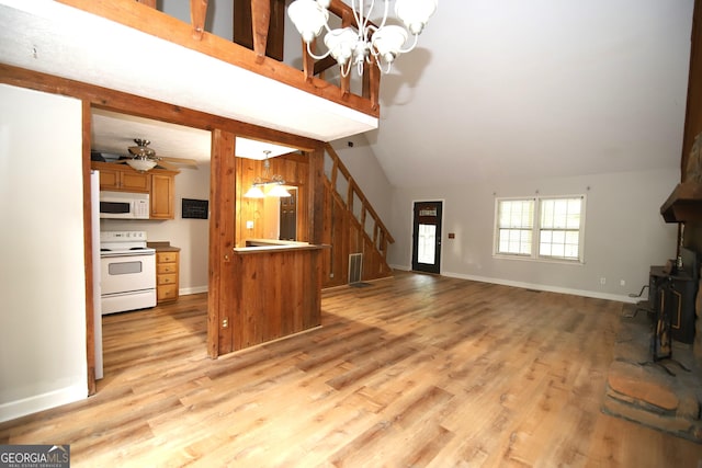 living room with ceiling fan with notable chandelier, light hardwood / wood-style flooring, and vaulted ceiling