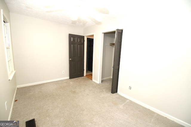 unfurnished bedroom featuring light carpet, a closet, and ceiling fan