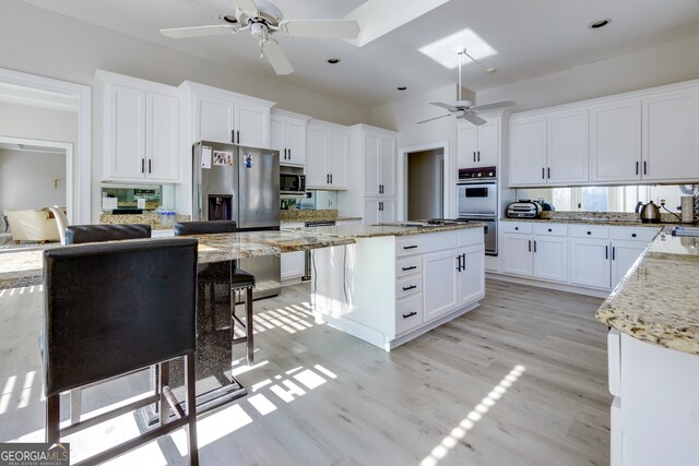 kitchen featuring light stone countertops, white cabinetry, a kitchen island, and stainless steel appliances