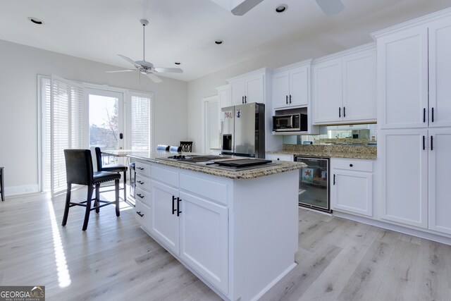 kitchen with appliances with stainless steel finishes, light wood-type flooring, white cabinetry, and wine cooler