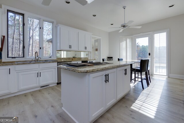 kitchen featuring white cabinetry, a kitchen island, plenty of natural light, and light hardwood / wood-style flooring