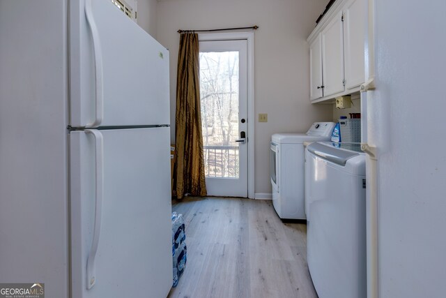 clothes washing area featuring cabinets, light hardwood / wood-style flooring, and washer and dryer