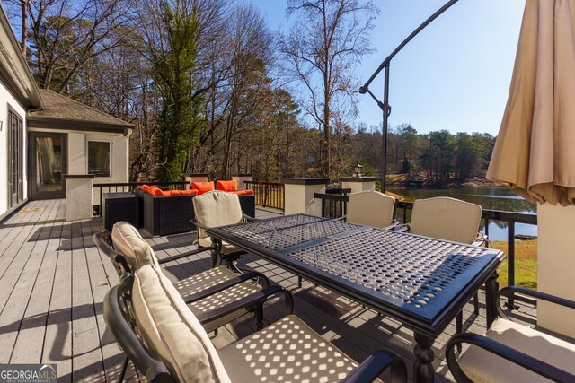 wooden terrace with a water view and an outdoor hangout area