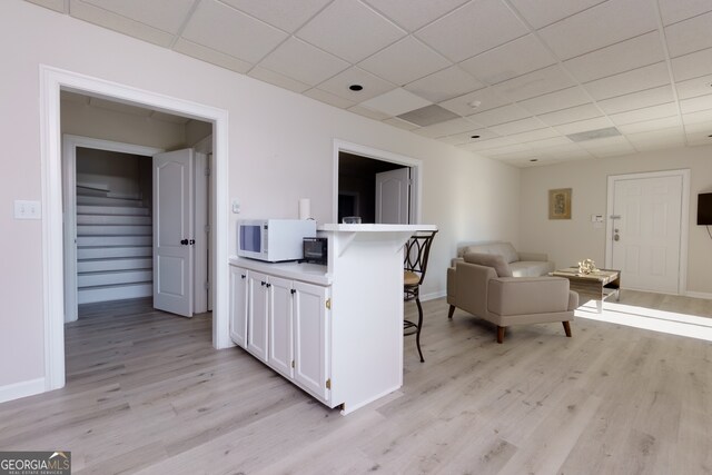 living room featuring a paneled ceiling and light hardwood / wood-style floors