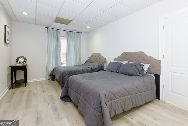 bedroom featuring a drop ceiling and light wood-type flooring