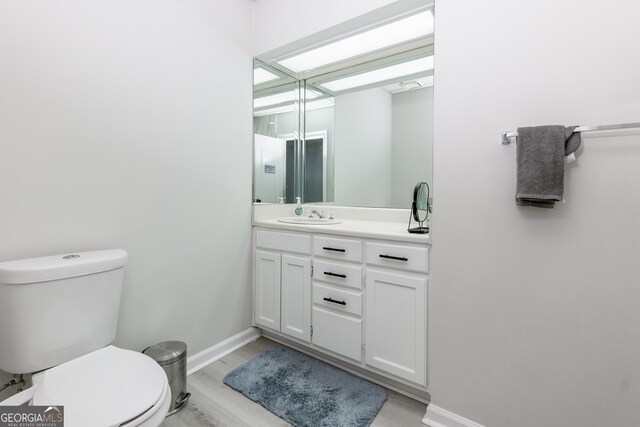 bathroom with hardwood / wood-style floors, vanity, and toilet