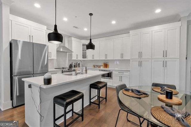 kitchen featuring stainless steel appliances, a sink, white cabinetry, wall chimney range hood, and dark wood finished floors