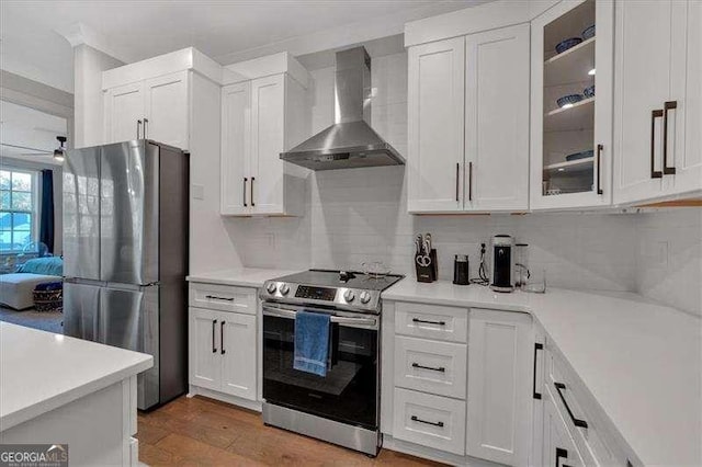 kitchen featuring white cabinets, wall chimney range hood, stainless steel appliances, and light countertops