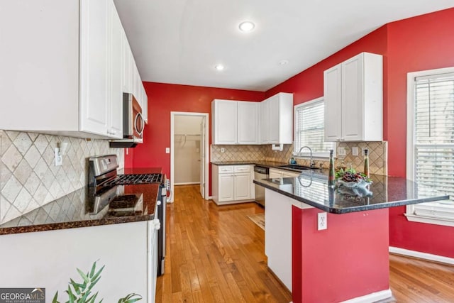 kitchen featuring a kitchen bar, sink, white cabinets, and appliances with stainless steel finishes