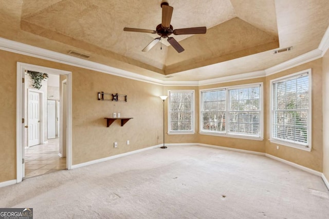 carpeted spare room with a raised ceiling, ceiling fan, and crown molding