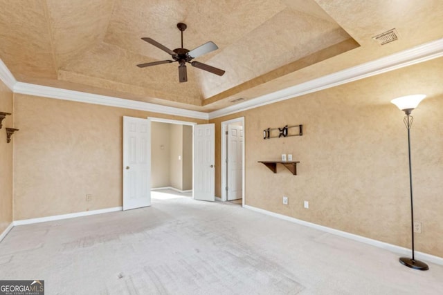 empty room featuring a towering ceiling, a tray ceiling, ceiling fan, crown molding, and carpet floors