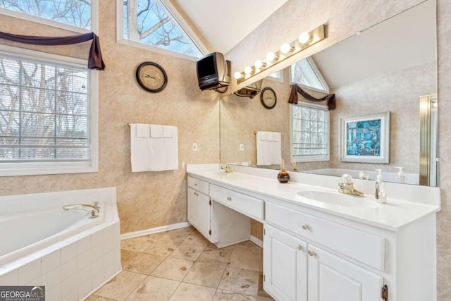 bathroom featuring vanity, vaulted ceiling, and tiled tub