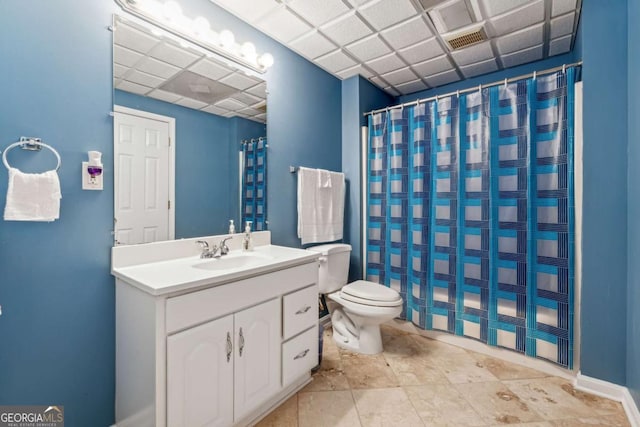 bathroom featuring a drop ceiling, toilet, and vanity