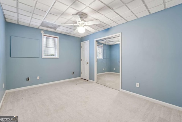 spare room featuring light carpet, a drop ceiling, and ceiling fan