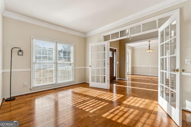 unfurnished room with crown molding, french doors, and hardwood / wood-style flooring