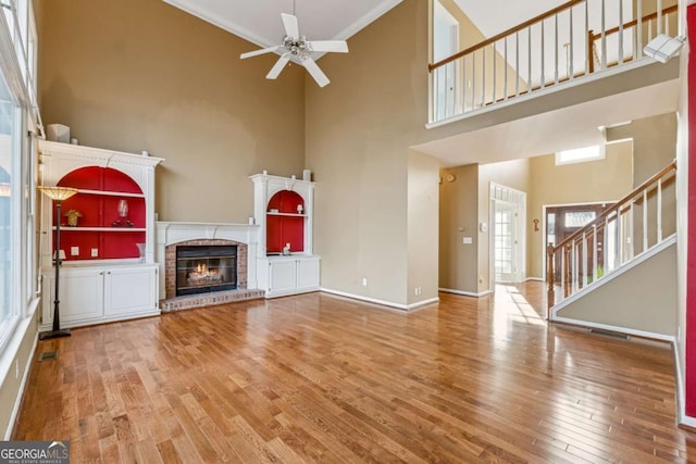 unfurnished living room featuring a fireplace, hardwood / wood-style floors, a healthy amount of sunlight, and a high ceiling