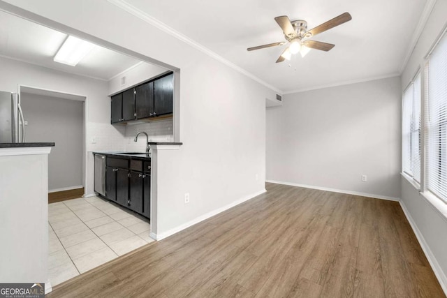 kitchen with appliances with stainless steel finishes, backsplash, a healthy amount of sunlight, and sink