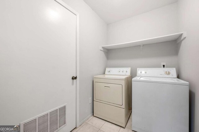 clothes washing area featuring light tile patterned floors and washer and dryer