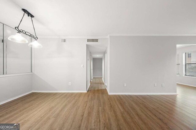 spare room with hardwood / wood-style floors and crown molding