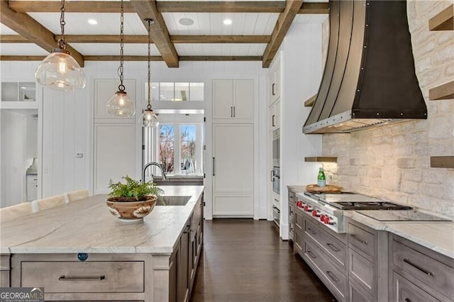 560 Lost River Bnd, Milton, GA 30004 - kitchen featuring wall chimney range hood, stainless steel gas cooktop, backsplash, beamed ceiling, and dark wood-type flooring
