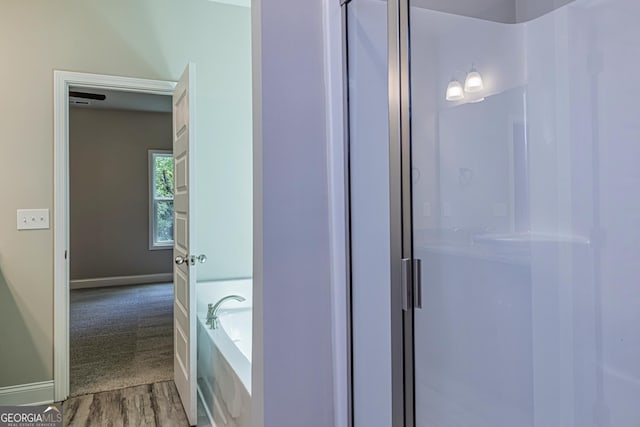 bathroom featuring wood-type flooring and plus walk in shower