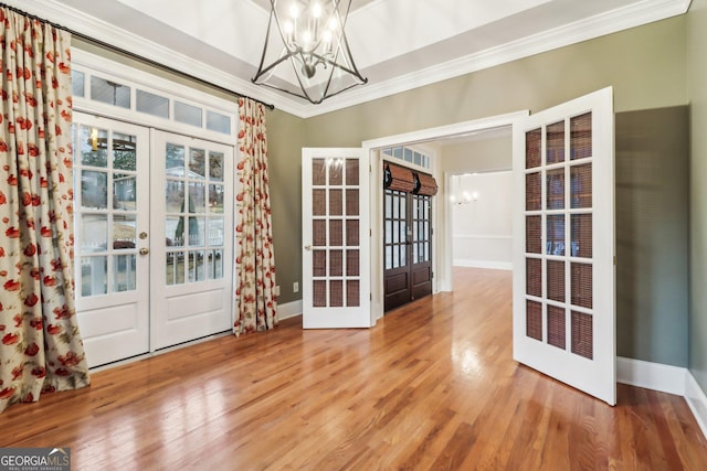 interior space with crown molding, french doors, a chandelier, and wood-type flooring