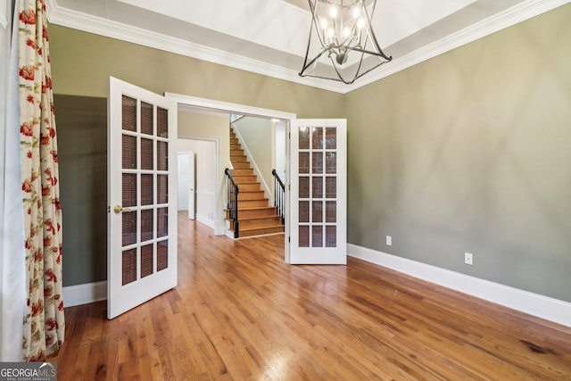 empty room featuring crown molding, french doors, wood-type flooring, and a notable chandelier