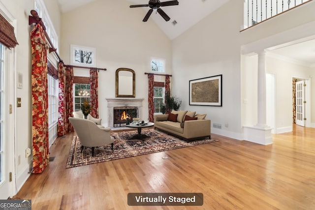 living room with light wood-type flooring, high vaulted ceiling, ceiling fan, and ornate columns